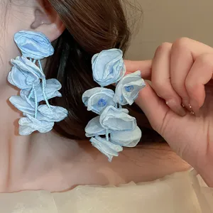 Primo piano di eleganti orecchini di fiori in tessuto blu con nappe di perline e argento.