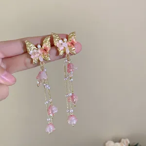 Charming butterfly drop earrings detail view, featuring delicate pink floral and pearl accents.
