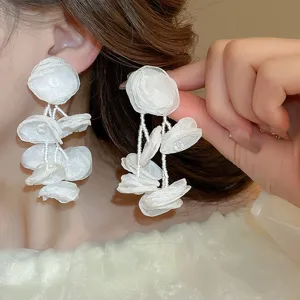 Primo piano dettagliato di orecchini con nappe di perline di fiori in tessuto bianco.