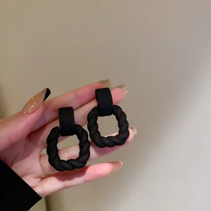 Matte black geometric twisted earrings detail shot, stylish and elegant daily wear accessory.
