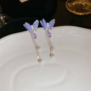 Close-up detail of purple butterfly tassel earrings with delicate chains and crystal drops.