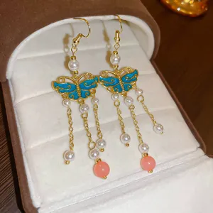 Detailed view of sweet fairy-style blue butterfly dangle earrings with pearls and pink bead drops.