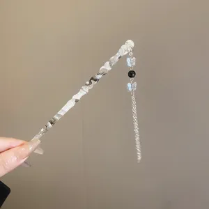 Détail en gros plan d'un pic à cheveux en résine noir et blanc avec pompon de papillon.