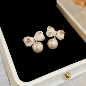 Elegant white bow pearl earrings with pink crystal and gold stars, chic high-end jewelry.