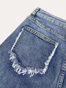 Close-up detail of light blue denim skirt pocket with raw frayed edge design.