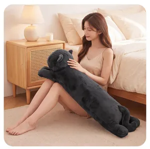 Detailed view of the long cat plush body pillow in a cozy bedroom setup with soft grey fabric.