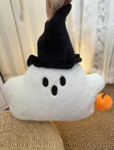 Dettaglio cuscino peluche fantasma Halloween, morbido giocattolo bianco con cappello da strega.