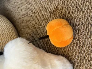 Dettaglio peluche fantasma di Halloween con corpo bianco morbido e accessorio zucca arancione.