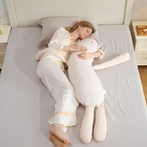 Close-up detail of soft striped long rabbit body pillow on bed with model sleeping.