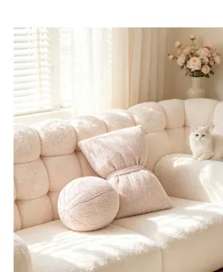 Detailed view of the pink plush bow pillow and round ball cushion in a cozy warm living room.