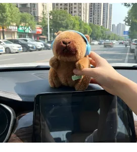 Cute cartoon capybara plush toy with blue headphones for car dashboard interior decoration