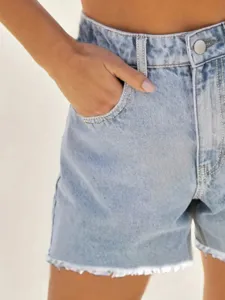 Detailed view of women's light blue denim shorts featuring raw frayed hems and metal button.