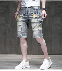 Men's light wash distressed denim shorts with vintage patched design and raw hem details.