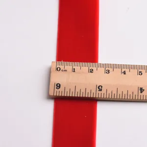 Red velvet ribbon detail showing width measurement with wooden ruler for DIY crafts.