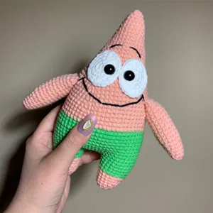 Handmade crochet plush doll toy, cute pink star cartoon character design, soft room decor.