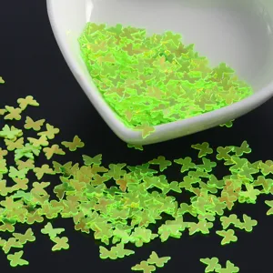 Neon green butterfly nail art sequins close-up detail shot for DIY crafts and sparkling makeup.