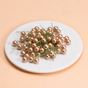Nahaufnahmedetails von goldenen künstlichen Beerenstielen mit grünem Draht für DIY-Handwerk.