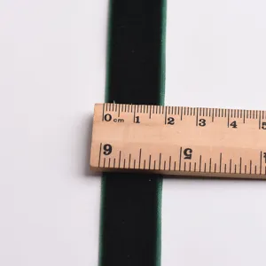 Dark green velvet ribbon detail close up showing width with a wooden ruler for DIY crafts.