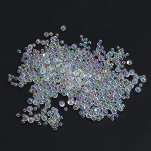 Detail shot of mixed-size transparent iridescent bubble beads with colorful pearl shine for crafts.