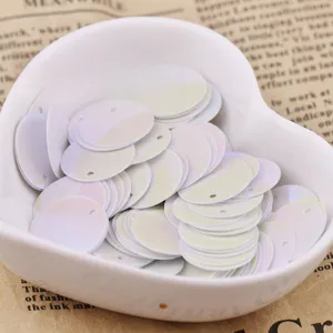 Close-up of 15mm white laser round sequins with hole in heart bowl, craft DIY accessory detail.