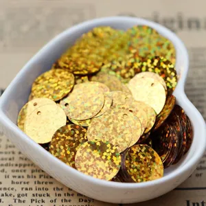 Detail view of 15mm gold laser sequins with hole for DIY crafts and apparel decoration.