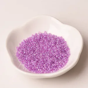 Close-up of 2mm light purple glass seed beads in a white ceramic dish for DIY jewelry making.