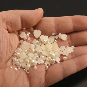 Close-up of assorted heart flatback pearls and round beads for nail art and phone case DIY.