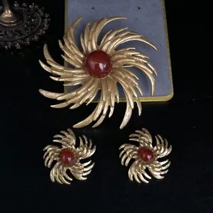 Vintage gold-toned starburst brooch and earrings set featuring red cabochon stone details.