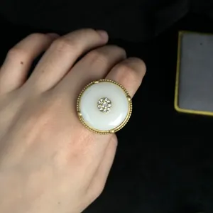 Close-up of vintage style safety buckle ring featuring white stone and rhinestone inlay detail.