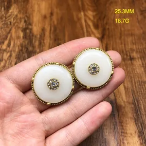 Detail view of vintage style safety buckle earrings featuring central rhinestone inlay and gold rim.