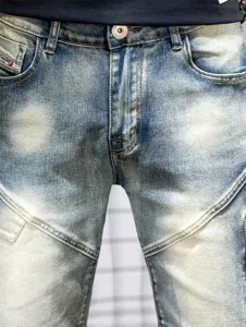 Close-up of men's distressed blue denim shorts featuring unique patchwork and metal button details.