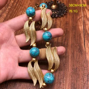 Detailed view of vintage turquoise stone and golden leaf necklace, elegant design statement jewelry.