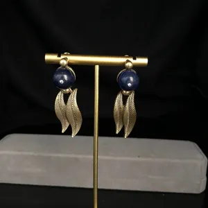 Detailed view of retro vintage style blue stone golden leaf dangling earrings jewelry.