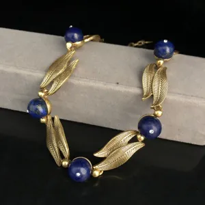 Vintage style gold-toned leaf and blue stone bead jewelry detail shot for women fashion.