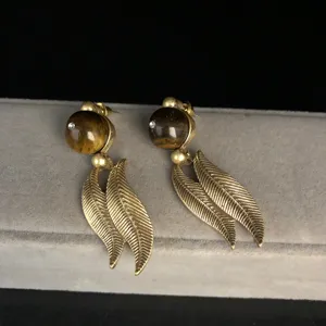 Vintage style gold tone leaf earrings detail shot, retro aesthetic metal drop jewelry piece.