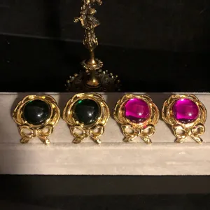 Detailaufnahme von Vintage-Ohrringen mit Schleifen-Design und farbigen Schmucksteinen im Hof-Stil.