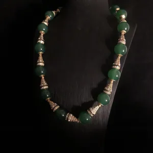 Close-up detail of vintage green beaded necklace with gold rhinestone cone spacers.