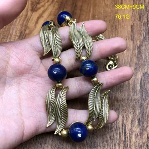 Vintage brass leaf and blue bead statement necklace, elegant retro design jewelry accessory.
