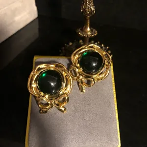 Elegante Ohrringe im Retro-Stil mit grünem Glasstein und feinem goldenen Schleifen-Design.