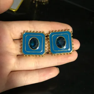Vue détaillée de boucles d'oreilles rétro émail bleu carré avec bordure dorée et cristal.