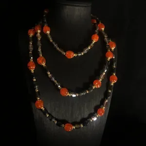 Vintage lange Perlenkette mit orangen Kürbis-Glasperlen und dunklen Steinen für Damen.