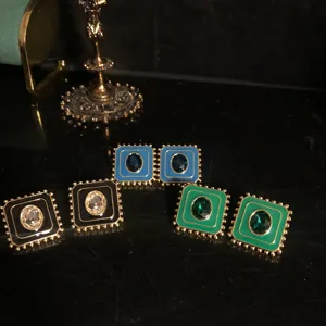 Détail de boucles d'oreilles carrées vintage en émail avec pierres colorées et bords dorés.