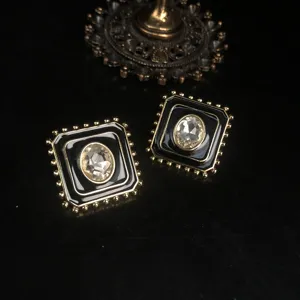 Boucles d'oreilles clous carrées en émail vintage avec un design géométrique noir et doré.