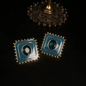Vue en gros plan detaillee des boucles d'oreilles carrees emaillees avec gemme bleue.