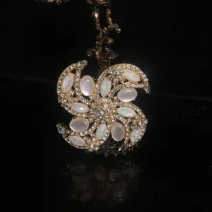 Vintage Luxus Goldfarbene Brosche mit weißen Opal Cabochons und funkelnden Strasssteinen.