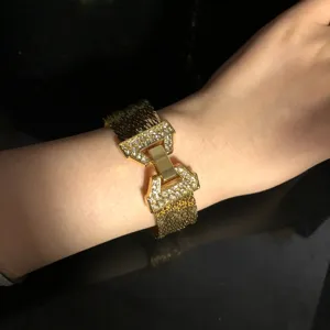 Close-up detail of a wide gold-plated mesh cuff bracelet with sparkling crystal geometric clasp.