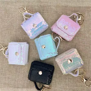 Close-up detail showing multiple colorful sequin mini bag charms with gold keychains on linen fabric.