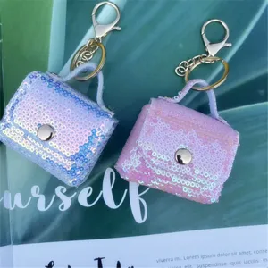 Macro detail of two iridescent sequin mini bag keychains with elegant gold hardware