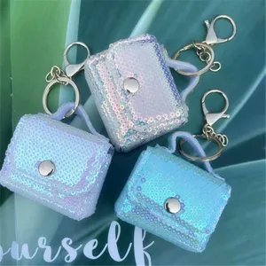 Detail view of colorful sequined mini bags as keychains on a green leaf background