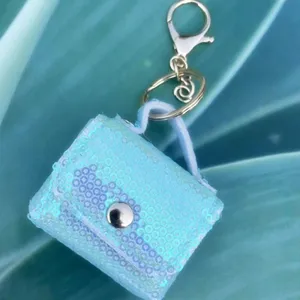 Macro detail of a light blue iridescent sequined mini bag pouch keychain for earphones